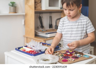 Bayi laki-laki membuat figur plastisin dengan elemen kacang kering untuk menghias kerajinan seni perkembangan awal di atas meja. Permainan anak laki-laki untuk mempelajari biji-bijian, keterampilan motorik halus sensorik dengan bahan alami