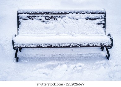 Клупа во паркот покриена со снег во зима. Зимско време и концепт на првиот снег.