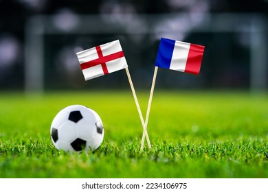 England - Perancis. Perlawanan bola sepak suku akhir. Pusingan 8. Bendera negara buatan tangan dan bola sepak di atas rumput hijau. Stadium bola sepak di latar belakang. Ruang edit hitam.