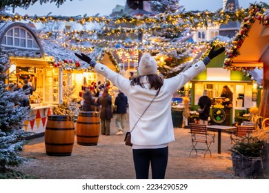 O femeie turistă fericită stă pe o piață de Crăciun din Copenhaga, Danemarca, cu decorațiuni iluminate în timpul amurgului de iarnă