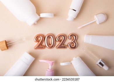 从柔和背景的容器中俯瞰化妆品框架。上面的玫瑰金数字 2023。适合新年优惠和文字叠加。