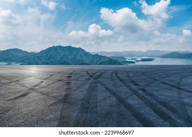 Jalan aspal dan pegunungan dengan pemandangan alam danau di bawah langit biru