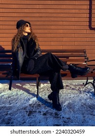 La dama del glamour se sienta en el banco al aire libre. Modelo de moda posando al aire libre en invierno.