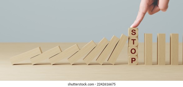 Mano che ferma l'effetto crisi aziendale del domino di legno o concetto di protezione dal rischio
