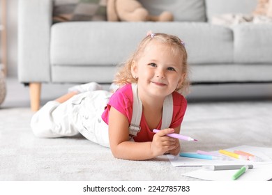 Niedliches kleines Mädchen zeichnet mit Filzstift auf dem Boden zu Hause
