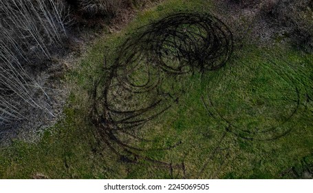 evidence of damage to agricultural land by car skidding. the police use a drone to document the damage after youths rampage in cars on the meadow. ruts into circles from spinning tires, landscape