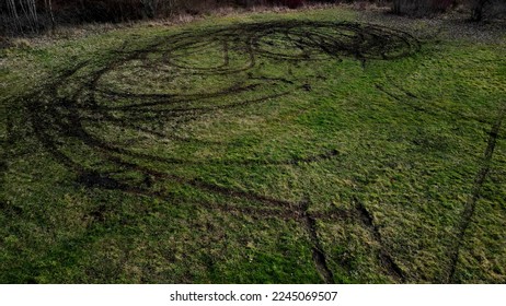 evidence of damage to agricultural land by car skidding. the police use a drone to document the damage after youths rampage in cars on the meadow. ruts into circles from spinning tires, landscape