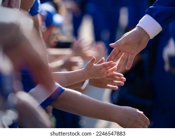 スポーツアリーナの外を通り過ぎるときに、スポーツヒーローにハイタッチをしている数人の小さな子供たち。スポーツ スターと手を触れている若い男の子の写真をクローズ アップ