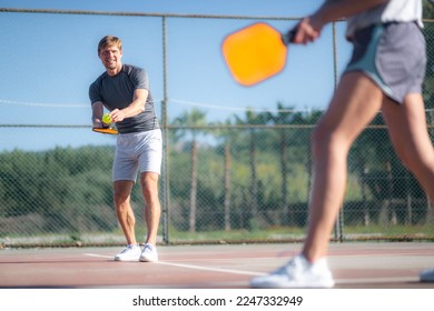 paartjie wat piekelbal speel, piekelbal geel bal met roei slaan, buitelugsport ontspanningsaktiwiteit.