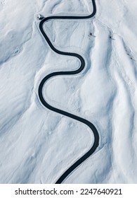 雪に覆われた山の丘にある曲がりくねった風の強い道​​。上空からの航空写真。上空から撮影した風光明媚な冬の背景。旅行のコンセプト。イタリア、ドロミテ、パッソ・ディ・ジャウ。