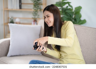 Donna asiatica che gioca ai videogiochi a casa. Gamer allegro che gioca online con la console.
