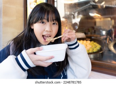 Elementary school girl eating while walking around Kamakura