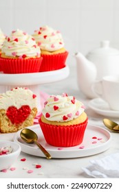Festlech Cupcakes mat engem Häerz bannen fir Vältesdag dekoréiert mat Spréngelen mat Häerzer op enger wäisser Plack. Léift Konzept. Selektiv Fokus.