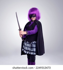 Girl kid, costume and sword in studio portrait for vigilante fantasy, creative and comic aesthetic. Child, superhero mask and creativity for martial arts, villain cosplay and halloween by background