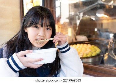 Elementary school girl eating while walking around Kamakura