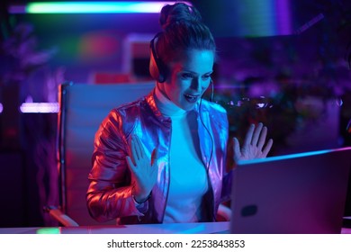 Neon metaverse futuristic concept. smiling modern business woman with laptop and headset having video call in modern office.