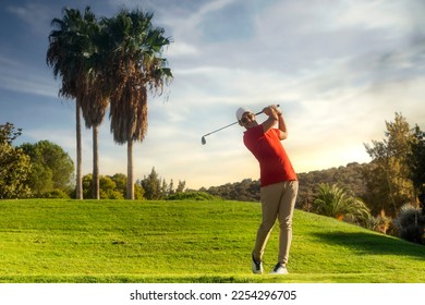 Golfschlagmann. Professioneller Golfschwung. Golfspieler beim Abschlag. Vorderansicht des Golfers, der seinen Schwung mit einem Lächeln beendet. In voller Länge des Golfers, der auf dem Platz spielt. Golfer, der mit dem Schläger einen Golfschlag macht