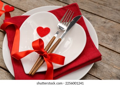 Table setting for Valentine's Day with bow and hearts on wooden background