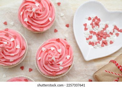 Baking paper with cupcakes for Valentine's Day on wooden background, closeup
