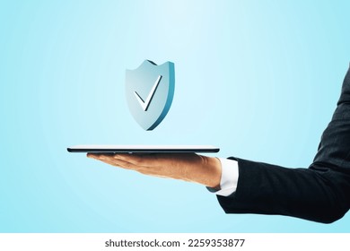 Koncept kybernetickej bezpečnosti a ochrany siete so začiarknutím na modrom štíte nad digitálnym tabletom v ruke podnikateľa na abstraktnom svetlom pozadí