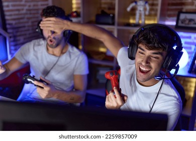 Zwee Hispanesch Männer Streamer spillen Videospill déi Aen bedeckt am Spillraum