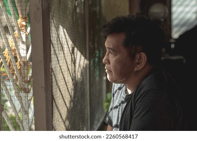 A saddened middle aged man peers through the screen window, longing for a loved one. Indoor dramatic scene.