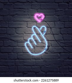 Düz ultraviyole neon renklerin kompozisyonu. Retro neon K-POP tabelası. Tuğla duvarda izole edilmiş renkli neon ışıklarla parmak kalp tabelası. Minimal aşk konsepti. Yaratıcı sanat, minimal estetik