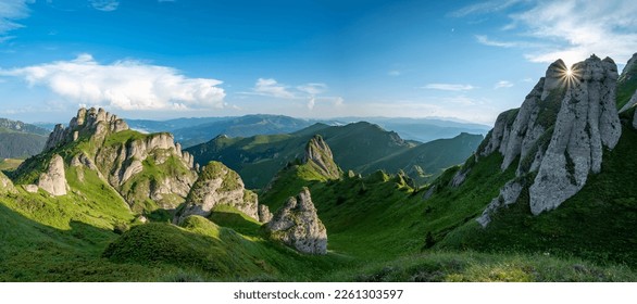 Panorama zelenega travnika s skalami in skalnatih gora v romunskih gorah v muntii ciucas z zahajajočim soncem