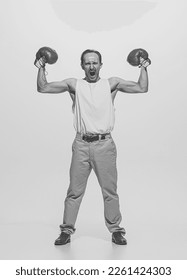 Porträt eines muskulösen Retro-Mannes in Vintage-Kleidung, der Muskeln in Boxhandschuhen zeigt und posiert. Schwarz-Weiß-Fotografie. Konzept von Sport, Hobby, aktivem Lebensstil, Retro-Mode. Platz für Anzeige kopieren