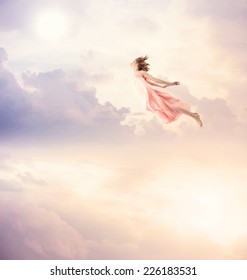 Girl in a pink dress flying in the sky. Serenity.