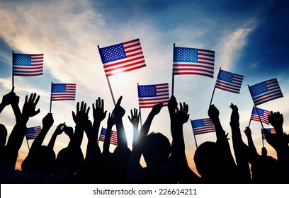 Sekelompok Orang Melambaikan Bendera Amerika saat Matahari Terbenam