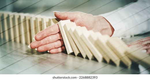 Mano femminile che ferma l'effetto domino. Concetto di controllo aziendale, modello geometrico