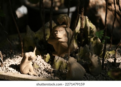 Büyük bir baba maymun ve etrafındaki küçük maymunlardan oluşan, birinin kafasında olduğu, gerçek maymunların vahşi doğadaki davranışlarını taklit eden, kaya ve bonsai ağaçlarının arka planında yer alan minik maymun bebeklerinin yakın çekim görüntüleri.