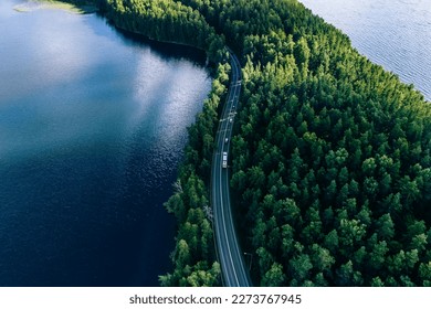 Aerial view of road in green woods and blue lakes water in summer Finland