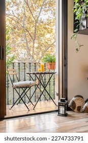 Vista dalla camera sul balcone con tavolo ed eleganti elementi decorativi, con tavolino e sedia con succo d'arancia che si affaccia sul parco con un paesaggio autunnale. Concetto di un appartamento accogliente.