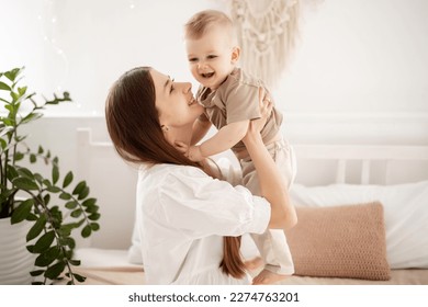 una giovane e bella madre con un bambino che si abbraccia sul letto a casa in camera da letto, cura e amore della madre, ritratto di una madre felice con un bambino, maternità sana