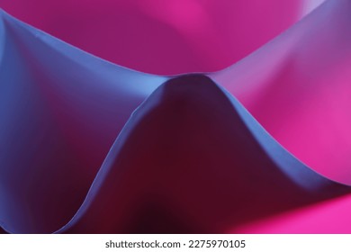 Papel de impresión de oficina con pliegues formando triángulos y ondas curvas con luz azul y rosa, forma un diseño abstracto muy original con fondo bokeh