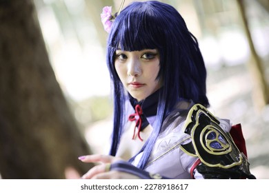 Portret i një loje të re të bukur cosplay me kostum fustan samurai në kopshtin japonez