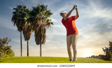 Golf je upucao čovjeka sa tee na rupi na golf terenu. golfer koji se kreće napolje puca sa dugim gvožđem na zalasku sunca u naočarima i viziru sa palmama u pozadini. zamutiti pozadinu