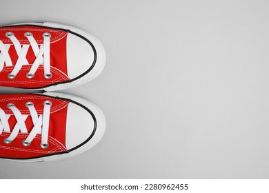 Paar neue stylische rote Turnschuhe auf hellgrauem Hintergrund, flach liegend. Platz für Text