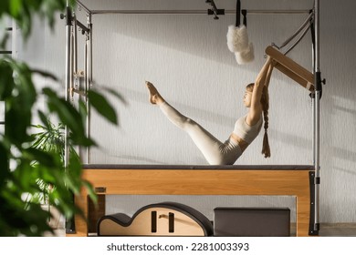 Pilates fitnes trener radi vježbe u pilates studiju. Balanced Body Cadillac mašina za fitnes treninge u teretani. Fiksno, zdravo i snažno autentično tijelo. Koncept fitnesa.