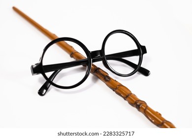 Anteojos negros redondos y varita mágica marrón aislados sobre fondo blanco. Anteojos y varita mágica estilo Harry Potter. Accesorios para disfraz de mago.