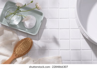 Một khay phấn màu hình chữ nhật có bình hoa và miếng bông đặt trên đó, bàn chải gỗ với khăn và chậu rửa được trưng bày. Không gian trống để quảng cáo sản phẩm mỹ phẩm