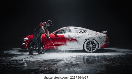 Especialista en lavado de autos que usa una hidrolavadora para enjuagar un auto deportivo moderno de color rojo. Un hombre adulto lava la suciedad y prepara un auto tuneado para el cuidado. Fotografía cinematográfica creativa en estudio