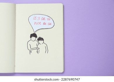 Carte avec la phrase It`s Ok to Not Be Ok, dessin d'une mère et de son fils dans un cahier sur fond violet, vue de dessus. Espace pour le texte