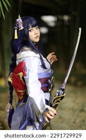 Portret i një loje të re të bukur cosplay me kostum fustan samurai në kopshtin japonez