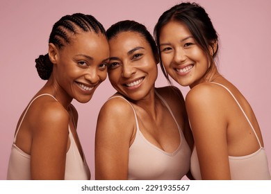 Kumpulan wanita yang pelbagai dengan pigmentasi yang berbeza . Wanita berbilang kaum dengan kulit cerah melihat kamera dan tersenyum.
