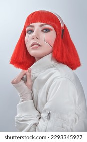 Immagine di un'attraente ragazza cyborg fantascientifica con trucco rosso acceso e capelli rossi alla moda. Concept cyberpunk. Trucco e acconciatura. Sfondo bianco.