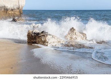 Großer Felsen, der neben einem Strand aus dem Meer ragt