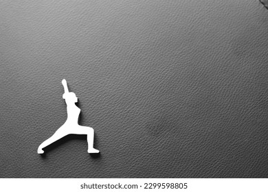 Silhouette of a woman on a black background in a yoga pose. Female figure on a dark background of illustrative type. Warrior pose in the world of yoga. Stretch in a standing position.